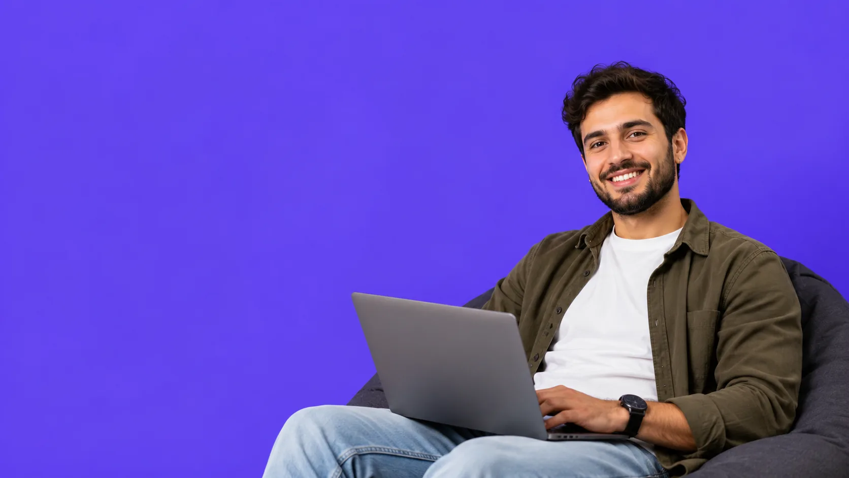 Un freelancer trabajando con su laptop sentado en un puff
