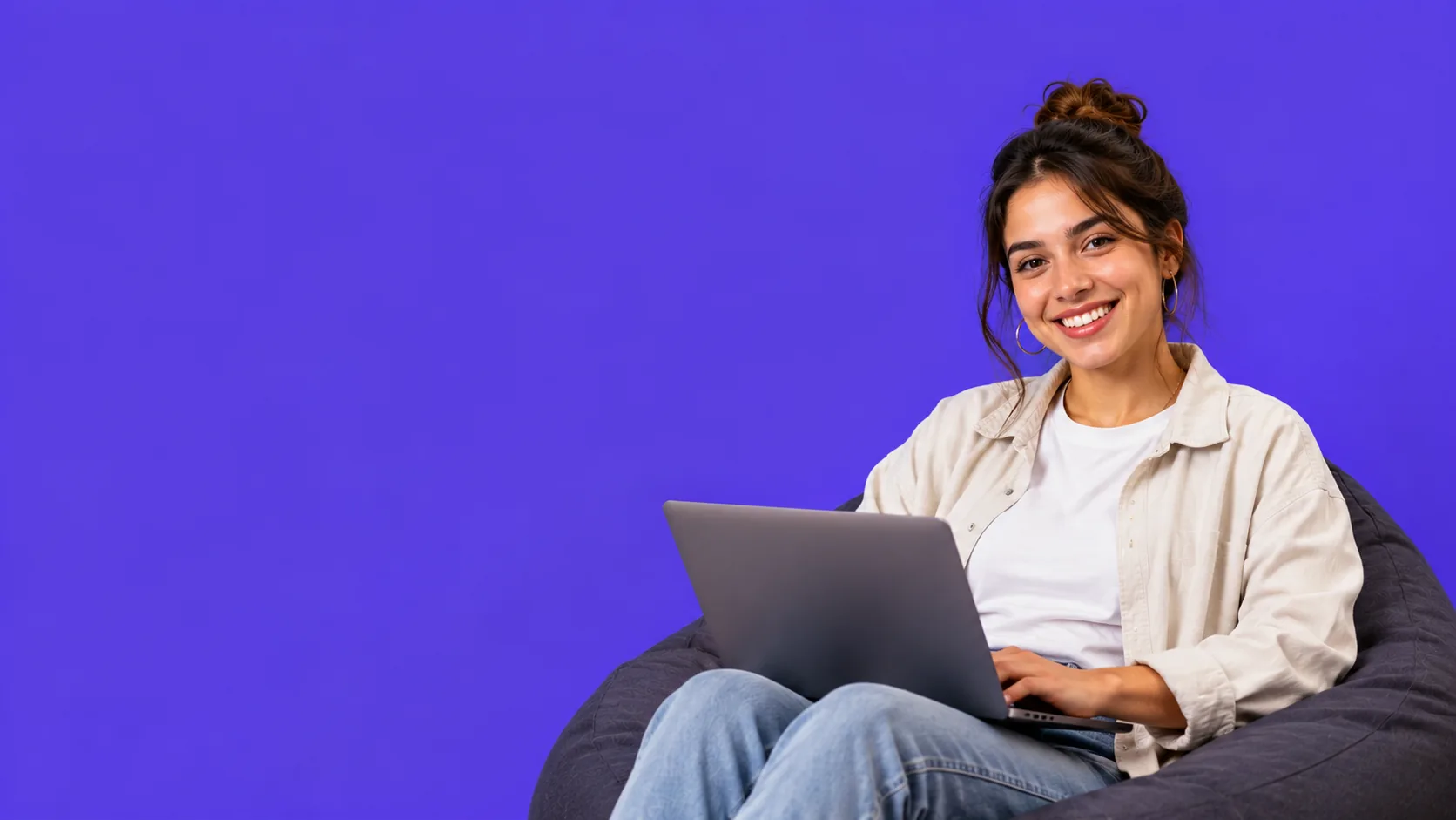 Una freelancer trabajando con su laptop sentada en un puff